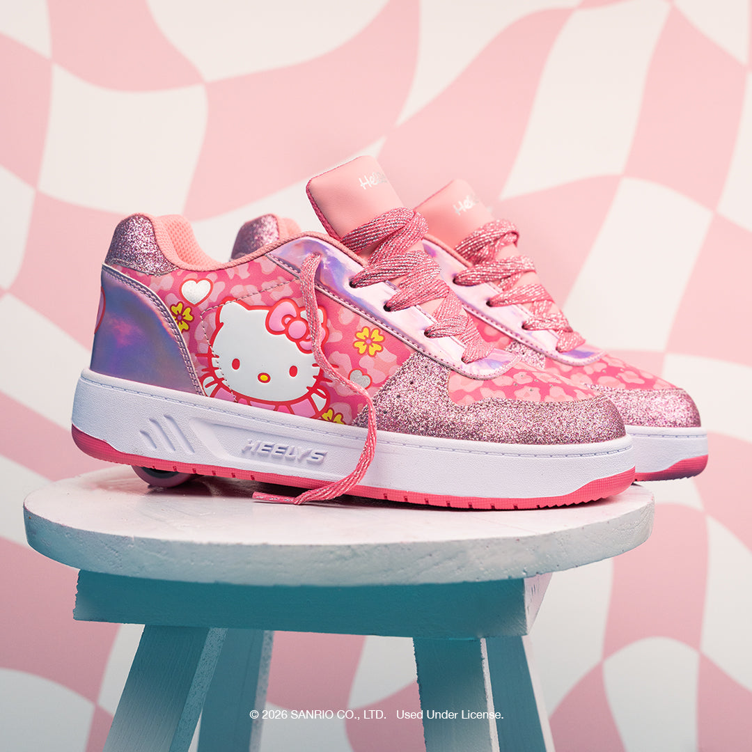Hello Kitty-themed pink sneakers on a small stool with a striped background
