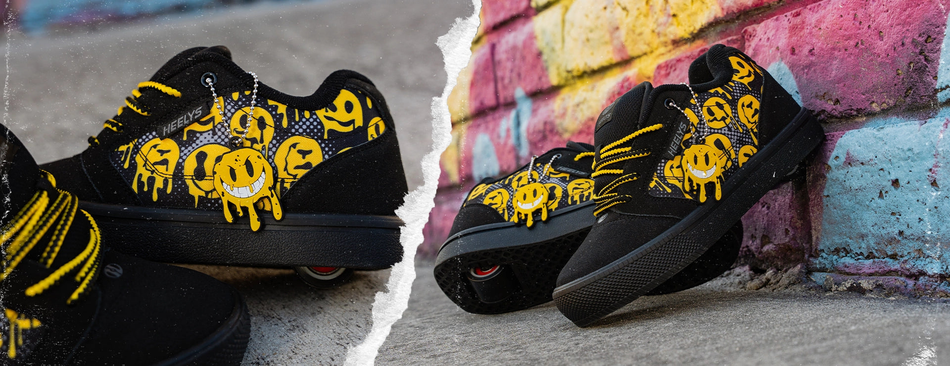 A pair of black low-top Heelys sneakers with yellow dripping smiley face graphics and yellow laces, shown in a split composition against a graffiti wall and concrete ground.
