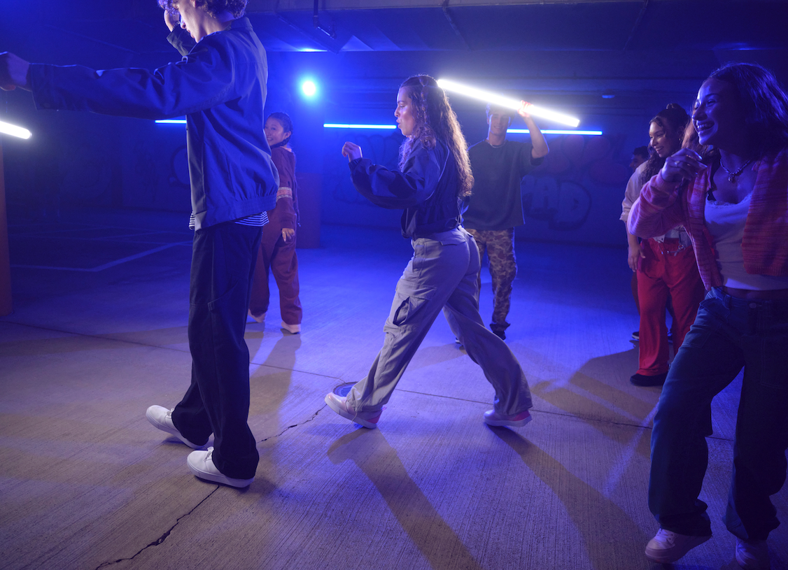 Group of people in a dance or performance setting with blue lighting
