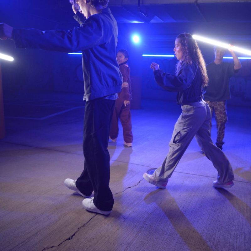 Group of people in a dance or performance setting with blue lighting